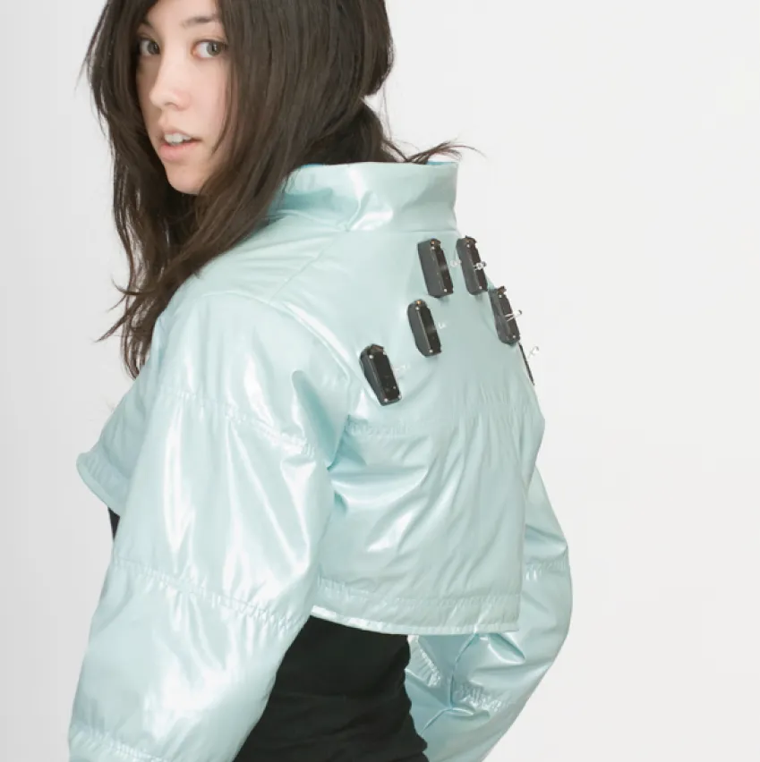 A young woman wearing a cropped puff jacket with motors on the back panel