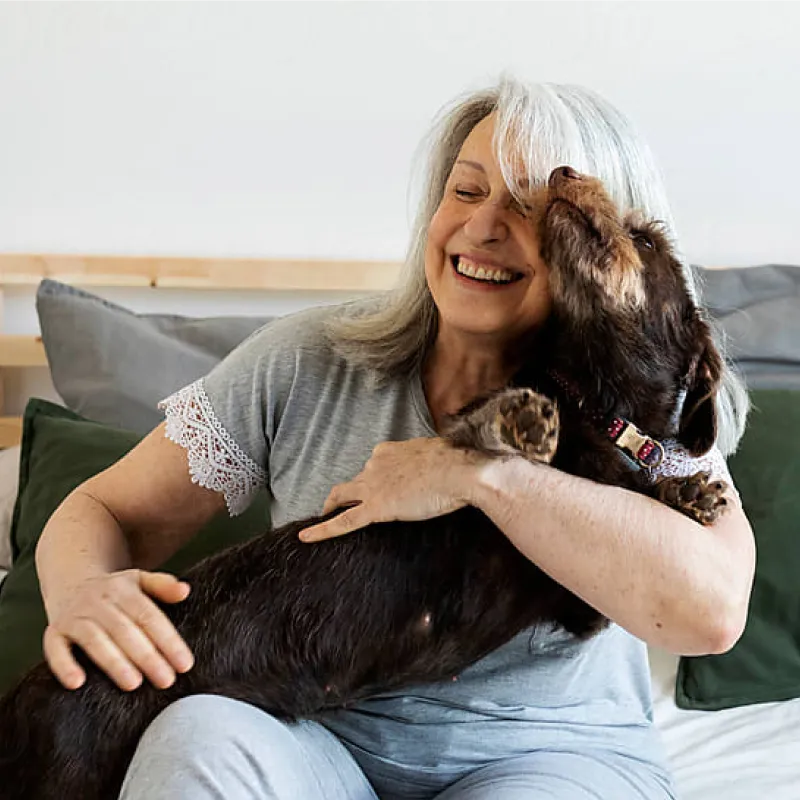 Mature woman with silver hair hugging a dog