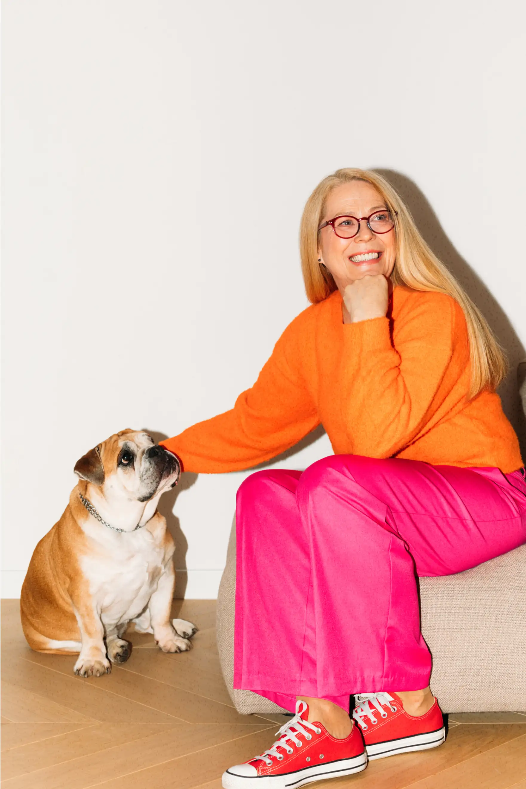 Long haired woman in 40-50s wearing bright color clothes, sitting with a dog