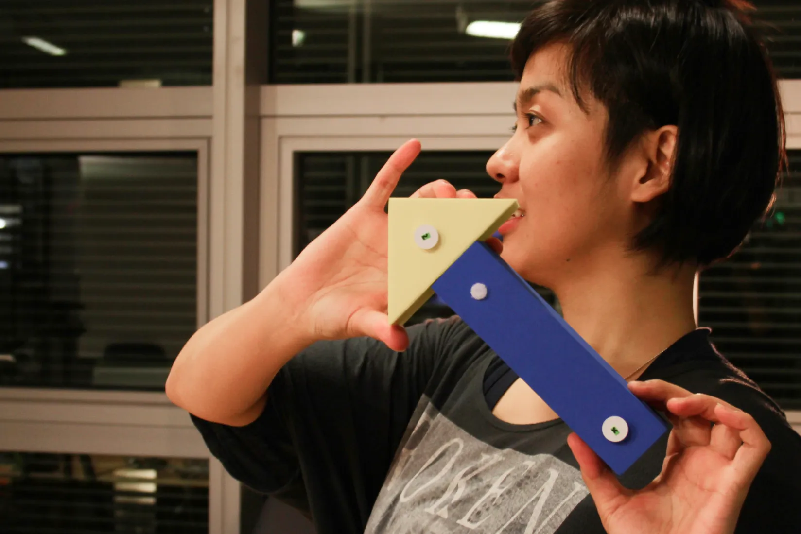 Person holding a geometric toy prototype shaped like an arrow, composed of angular foam pieces and with RFID tags glue on.