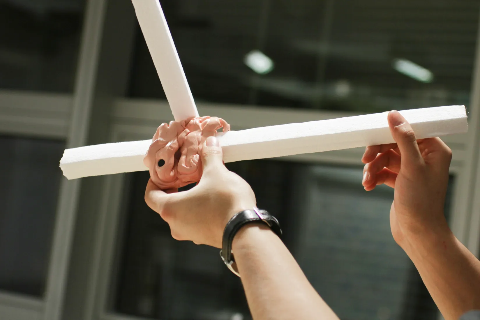 Two-handed interaction with an assembled toy prototype made from intersecting white rods.